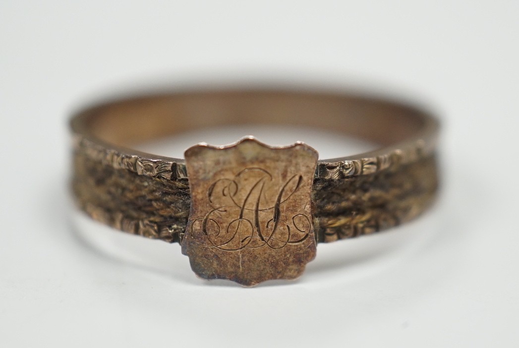 A Victorian yellow metal mourning ring, with engraved monogram and shank inset with plaited hair, size O, gross weight 1.2 grams.